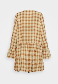 Top xadrez em bege e castanho com mangas largas, bainha em babados e corte relaxado. Feito de um tecido leve com uma textura suave.