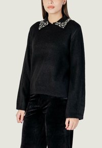 Suéter negro de punto con un ajuste cortado, que presenta un cuello decorativo adornado con cuentas blancas. Mangas largas y detalle de dobladillo acanalado.