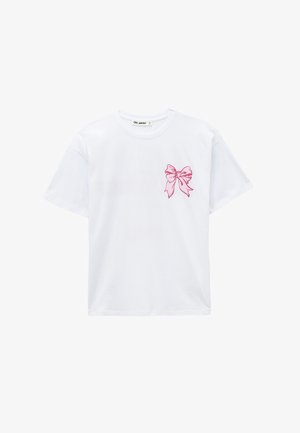 T-shirt blanc à manches courtes avec un petit nœud rose imprimé sur le côté gauche de la poitrine et un col rond.