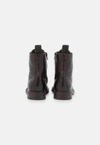 Bottines en cuir marron à finition lisse, bout arrondi et fermeture éclair à l'arrière. Dotées de languettes de tirage vertes et d'un petit talon carré.