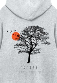 Schwarze Silhouette eines blattlosen Baumes mit fliegenden Vögeln nahe einer orangefarbenen Sonne, vor einem grauen Kapuzenpullover-Hintergrund mit dem Text "ESCAPE" darunter.
