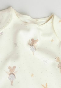 Cream-colored baby garment with soft mouse fairy and star patterns, featuring wings, magic wands, and small bows printed on fabric.