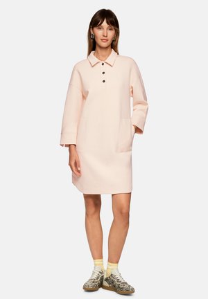 Hellrosa Baumwollkleid mit Kragen, drei schwarzen Knöpfen und zwei vorderen Taschen. Mit langen Ärmeln und lockerem Sitz.