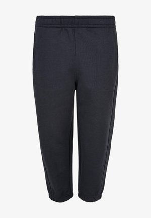 Czarna koszulka krótki rękaw zestawiona z granatowymi spodniami dresowymi z elastycznym pasem, uzupełniona białymi trampkami dla uzyskania swobodnego wyglądu.