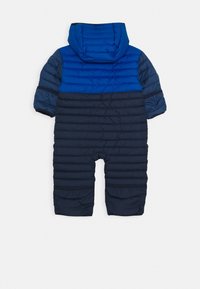 Sininen ja tummansininen paksu lumipuku, jossa on huppu, vaakasuorilla ompeleilla ja elastisilla hihansuilla lämmön ja istuvuuden takaamiseksi. Takakatsaus esitetty.