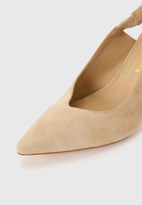 Μπεζ σουέντ παπούτσι με μυτερή μύτη και λουράκι στο πίσω μέρος, με χαμηλό κόψιμο στο πάνω μέρος και επένδυση από λείο δέρμα στο εσωτερικό.