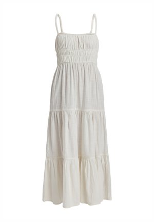 White maxi dress made of lightweight fabric with a smocked bodice, thin shoulder straps, and tiered ruffles at the hem.