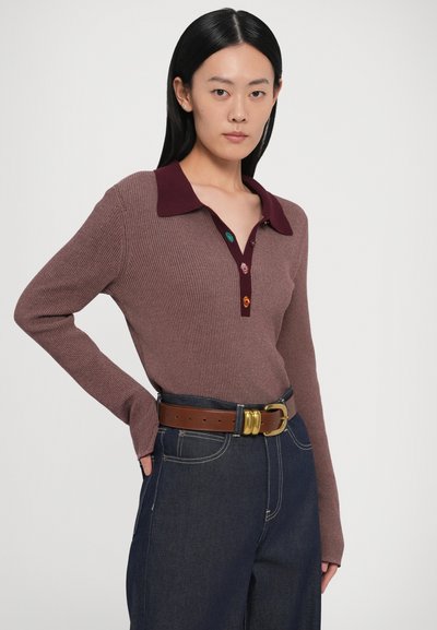Brūns ribots džempera polo krekls ar burgundijas krāsas apkakli, četri krāsaini pogas, sapārots ar tumšu džinsu un brūnu jostu ar zelta sprādzi.