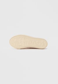 Talpa de pantof bej deschis, cu cauciuc texturat, având numele mărcii repetat, embossat pe întreaga suprafață. Design de tip tălpi circulare pentru aderență.