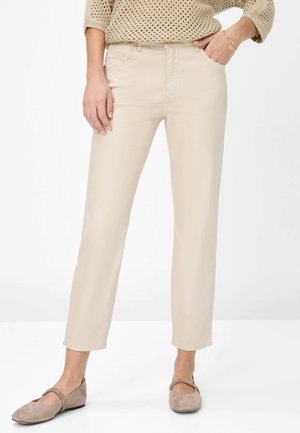 Beige Knöchellange Hosen aus glattem Stoff, mit Fronttaschen, maßgeschneidertem Schnitt und dezenten Nähdetails.
