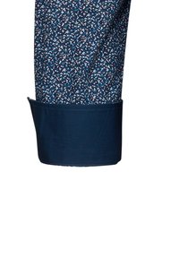 Pantaloni da uomo con un motivo a pois blu e bianco, realizzati in un tessuto morbido. Il bordo è di un blu navy uniforme con una finitura pulita.