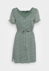 Vestido verde con lunar, con escote en V, mangas cortas con volantes, cintura ceñida y una silueta fluida. Hecho de una tela ligera con una textura suave.