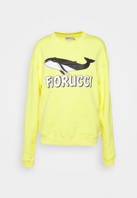 Sudadera amarilla con un gran gráfico de una ballena en blanco y negro y el texto "Fiorucci" en la parte frontal. Fabricada en una suave mezcla de algodón.