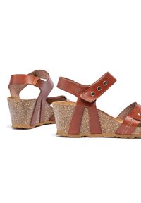 Bruine leren wedge sandalen met een kurk-textuur zool. Beschikt over verstelbare banden en stijlvolle uitsparingen aan de zijkanten.