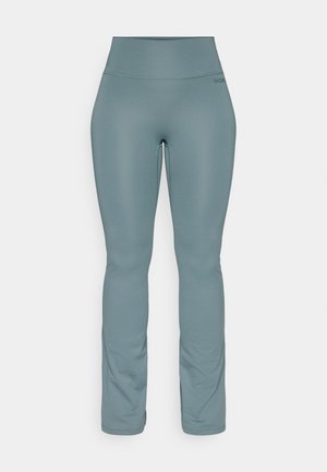 Vysoké, slim-fit tyrkysové legíny s mírným rozšířením u kotníků, vyrobené z hladkého pružného materiálu, vystavené na obyčejném bílém pozadí.