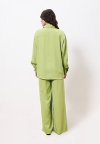 Groene oversized blouse en bijpassende wijde broek, lichte stof, met kraagontwerp, lange mouwen en een ontspannen pasvorm met subtiele glans.