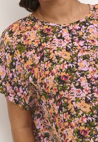 Haut à manches courtes floral avec un motif multicolore aux nuances de rose, orange, vert et noir. Tissu doux et encolure ronde.