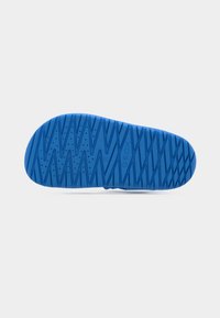 Blå gummisåle med teksturert, mønstret overflate med diagonale riller og små perforeringer, merket med "GEOX" og størrelse 27.