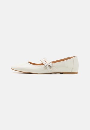 Ballerines en cuir verni blanc avec un bout pointu, deux sangles décoratives avec des boucles en argent, et une semelle marron discrète.
