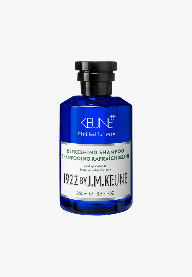 Bottiglia di vetro blu con tappo a vite nero. Presenta testi bianchi e verdi che leggono "Shampoo Rinfrescante" e "1922 di J.M. Keune." 250 ml.
