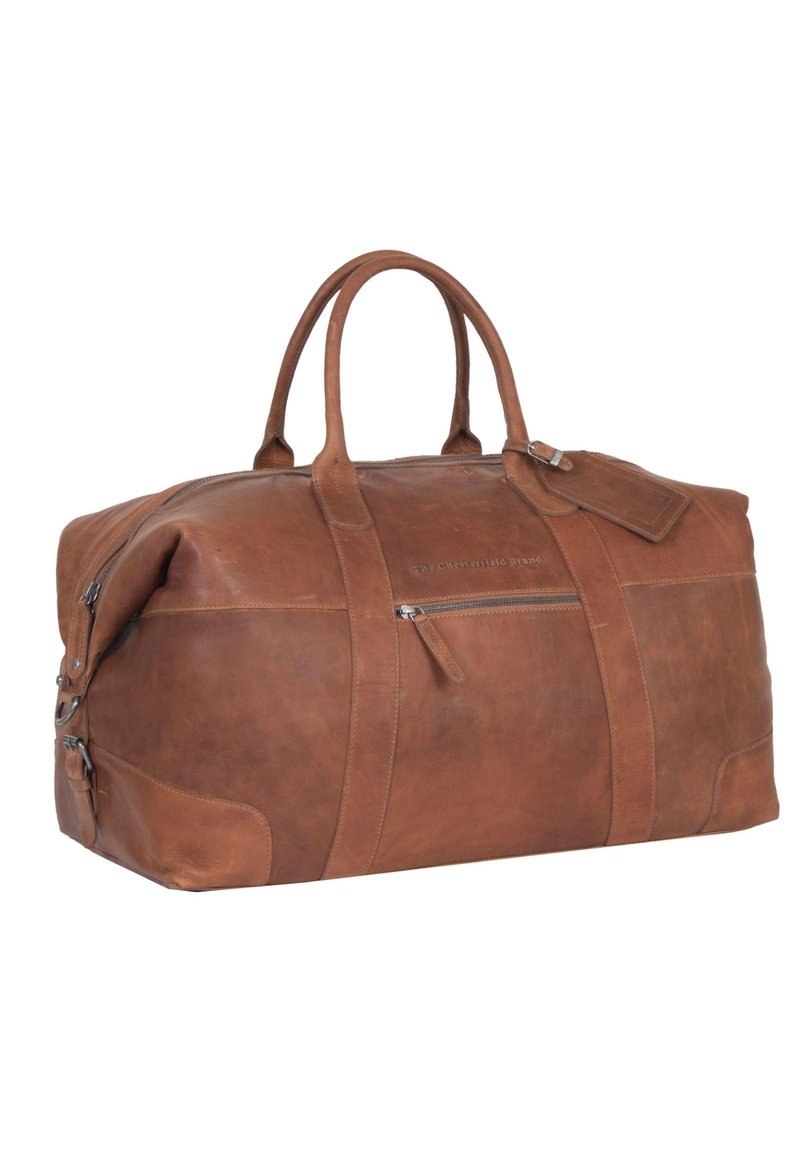 Borsa da viaggio in pelle marrone con doppio manico, tasca frontale con zip e etichetta per bagagli. Presenta una texture liscia e una forma arrotondata.