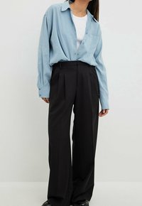Light blue long-sleeve shirt with a button-down collar, paired with high-waisted black wide-leg trousers, featuring front pleats.