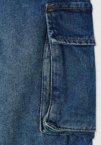 Tessuto denim di colore blu scuro con una tasca a toppa e cuciture arancioni a contrasto. La texture è liscia e leggermente sbiadita in alcune aree.