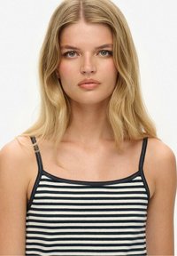 Stribet tanktop med tynde skulderstropper, prydet med marineblå og cremefarvede vandrette striber, blød bomuldsstruktur og en slank pasform.