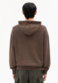 Bruine oversized hoodie met een zachte textuur, voorzien van een trekkoordkap, geribde manchetten en zoom. Draagt bij cargo broeken, weergegeven vanuit de achterkant.
