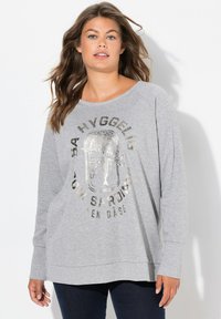 Sudadera gris de manga larga, con escote en forma de barco y print frontal con letras metálicas que presenta un diseño de lata de sardinas.