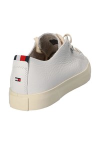 Sneaker bianca in pelle con suola crema, finitura testurizzata, lacci neutri e tacco posteriore con accenti a strisce rosso, bianco e blu.