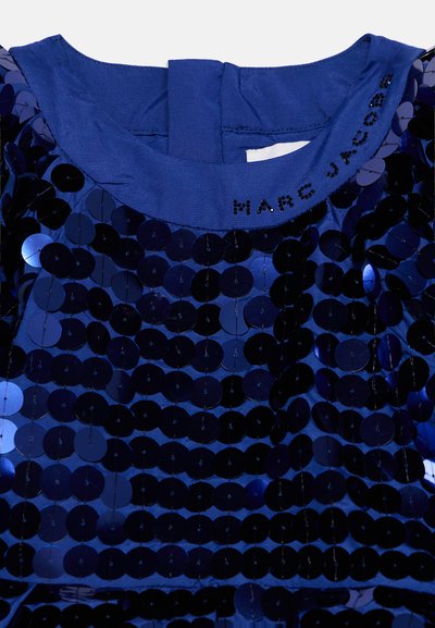 Крупен план на синя плат с пайети с яка с черни мъниста, изписващи Marc Jacobs.