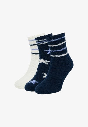 Set van drie gezellige sokken: marineblauw met witte strepen, effen wit, en marineblauw met sterrenpatronen. Zachte, fluffy textuur, enkelhoogte.