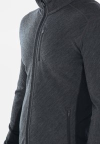 Giacca zip-front grigia scura, con texture, tasche laterali e colletto alto; presenta un design adattato e un tessuto resistente.