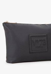 Borsa in pelle nera con superficie testurizzata, dotata di un'etichetta loggata rettangolare in rilievo e di un dettaglio con zipper dorato.
