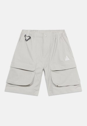 Jasnoszare szorty cargo z elastycznym pasem, przednim guzikiem, dużymi klapkowymi kieszeniami, bocznymi kieszeniami oraz małym metalowym karabińczykiem po lewej stronie.