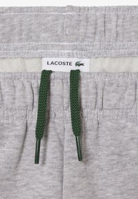 Pelēki kokvilnas šorti ar teksturētu apdari, ar zaļu auklu un Lacoste zīmolu jostas vietā.