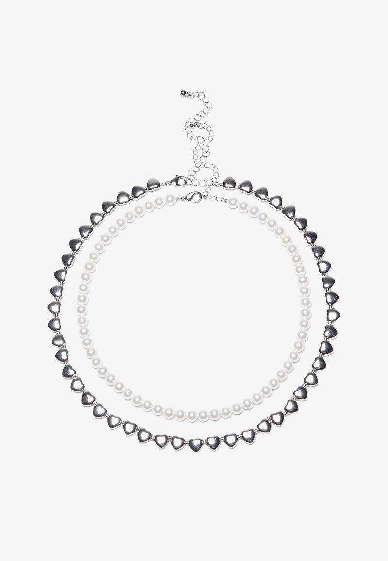 Kaksikerroksinen kaulakoru, jossa on hopeanvärisiä sydämenmuotoisia helmiä ja valkoisia helmiä. Säädettävä ketjukiinnitys varmasta istuvuudesta. Sujuva pinta ja kiiltävä viimeistely.