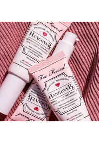 Two pink tubes of Too Faced Hangover RX replenishing face primer with white caps and gold accents, featuring logos and product details on labels.