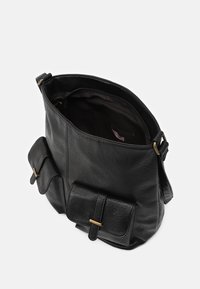 Černá kožená taška s jemnou texturou, vybavená dvěma předními kapsami, horním otevřením a ramenním popruhem pro nošení. Vnitřek není podšitý.