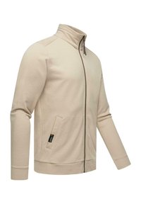Svijetlosmeđi zip-up jakna napravljena od mekanog materijala. Ima visoki ovratnik, bočne džepove i rebraste manžete. Jednostavan, elegantan dizajn.
