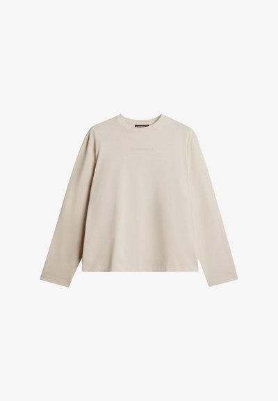 Ilgų rankovių kreminės spalvos marškinėliai, pagaminti iš minkštos medvilnės, su apvaliu kaklu ir įspaustu logotipu krūtinėje. Paprastas, tiesus kirpimas.