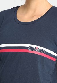 Camisa de color azul marino con rayas horizontales blancas y rojas y el logo "CMP" en el pecho, llevada por una mujer.