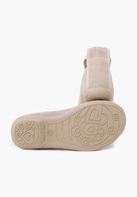 Scarpe in suede beige con tacco basso, caratterizzate da una suola in gomma testurizzata con motivi floreali e a cuore; elastico sul retro per una vestibilità sicura.