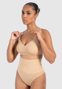 Nude draadloze beha met brede bandjes en een soepele textuur, gecombineerd met hoge taille, geribbelde seamless slipjes in bijpassende kleur.