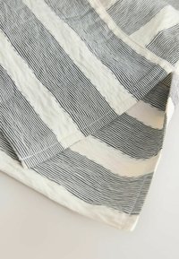 Gestreepte stof met afwisselend zwarte en witte lijnen in verschillende breedtes, met een zachte textuur en een lichte glans. Randen zijn gestikt.