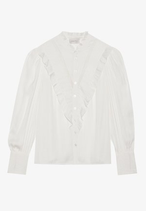 Hvit bluse med volangkrage og frontlufte, med lange ermer som har plissert detaljer og knapper foran.