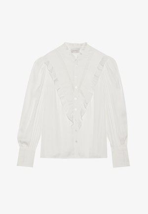 Blusa blanca con cuello volangado y abertura frontal, con mangas largas que presentan acentos plisados y botones en la parte delantera.