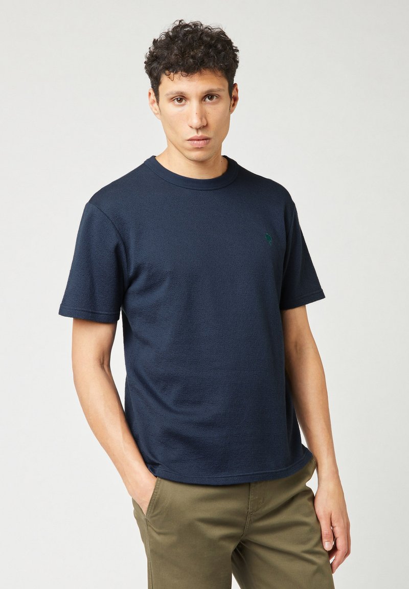 T-shirt blu navy a maniche corte realizzata in tessuto testurizzato, con scollatura rotonda e un piccolo logo verde sul petto.