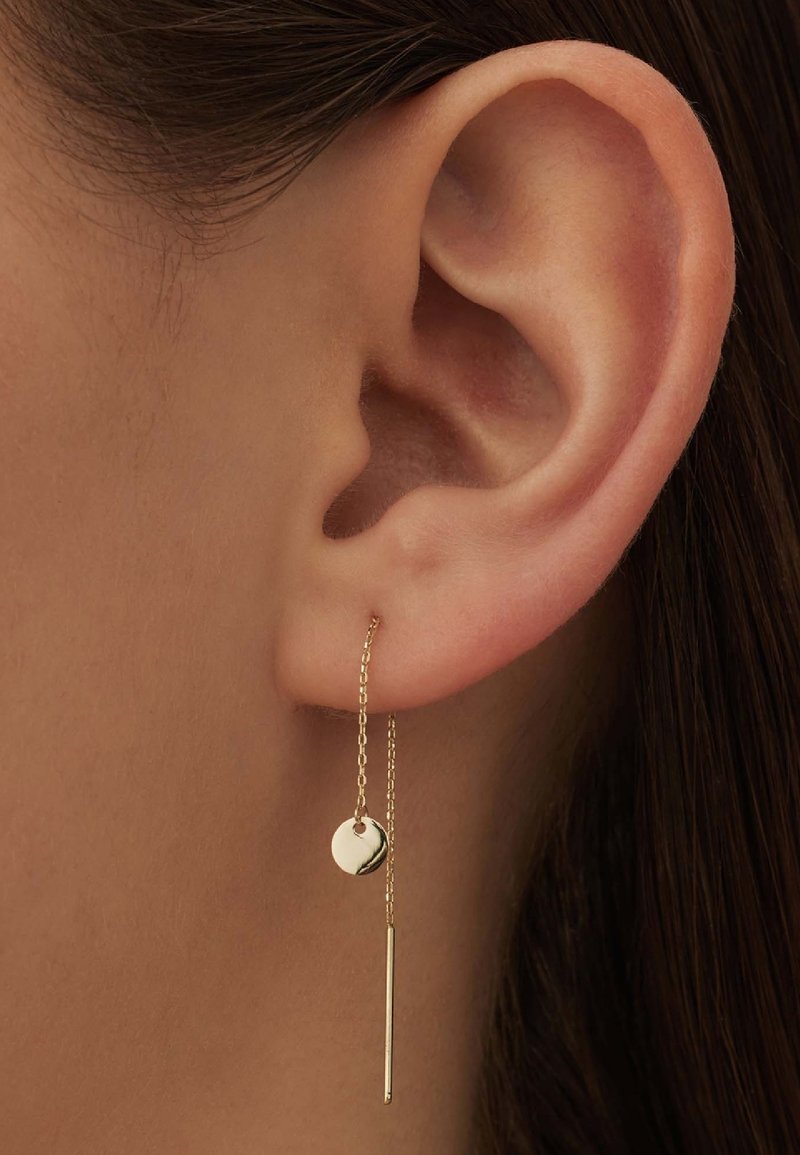 Goldohrringe mit einer runden Scheibe und einem schlanken Stab, die an einer zarten Kette hängen. Minimalistisches Design mit glatten Oberflächen.